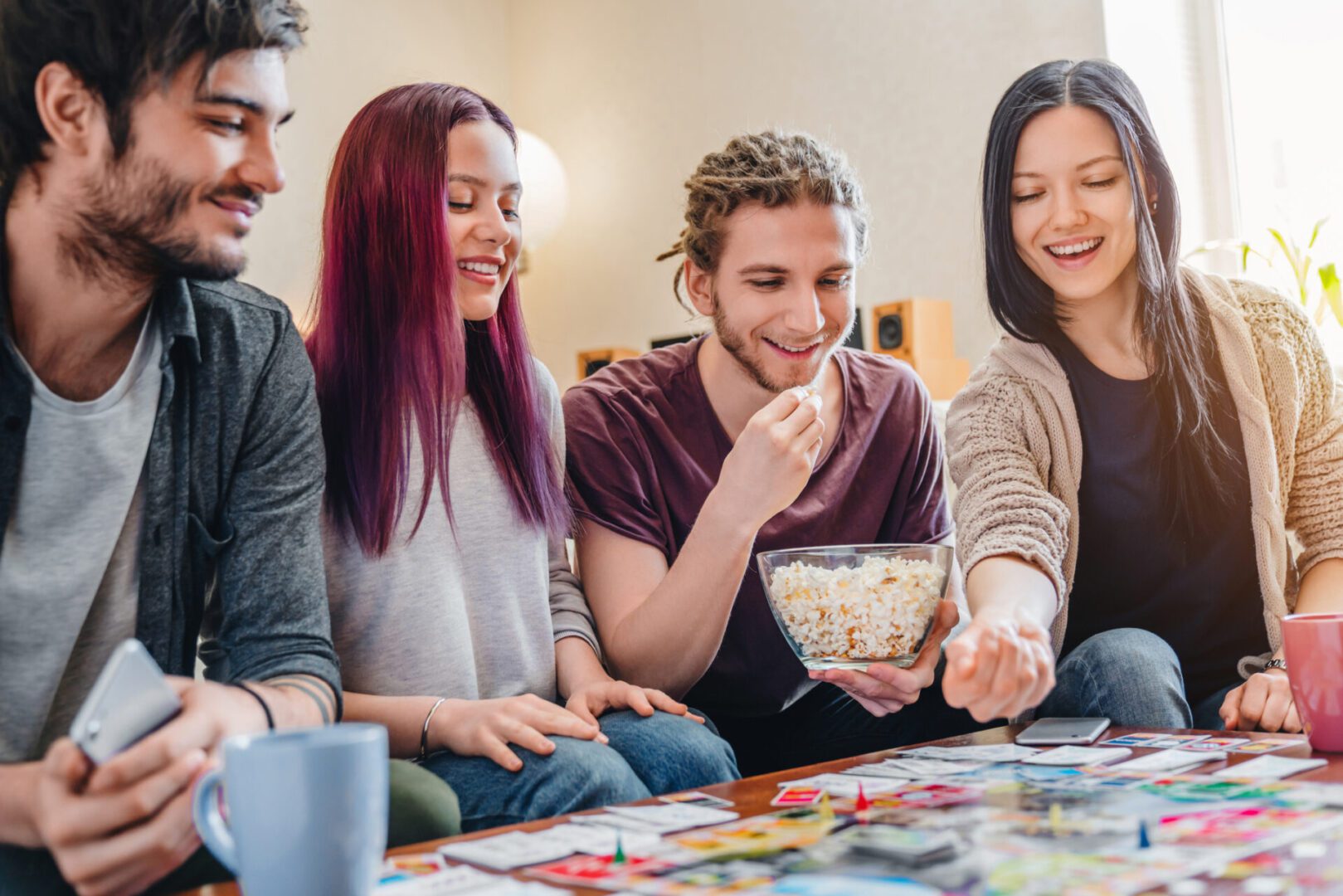 Friends playing board game and eating popcorn.