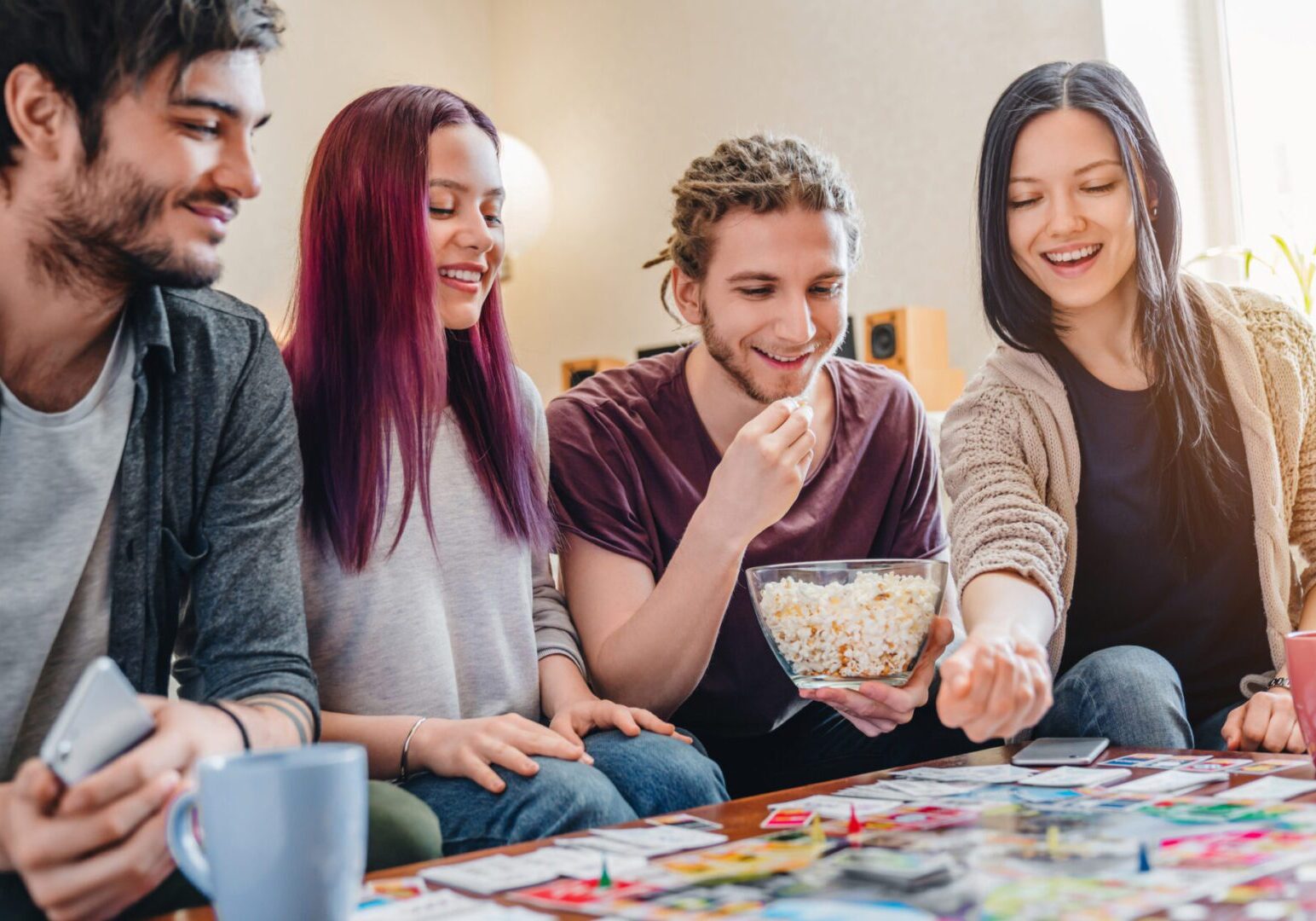 Friends playing board game and eating popcorn.